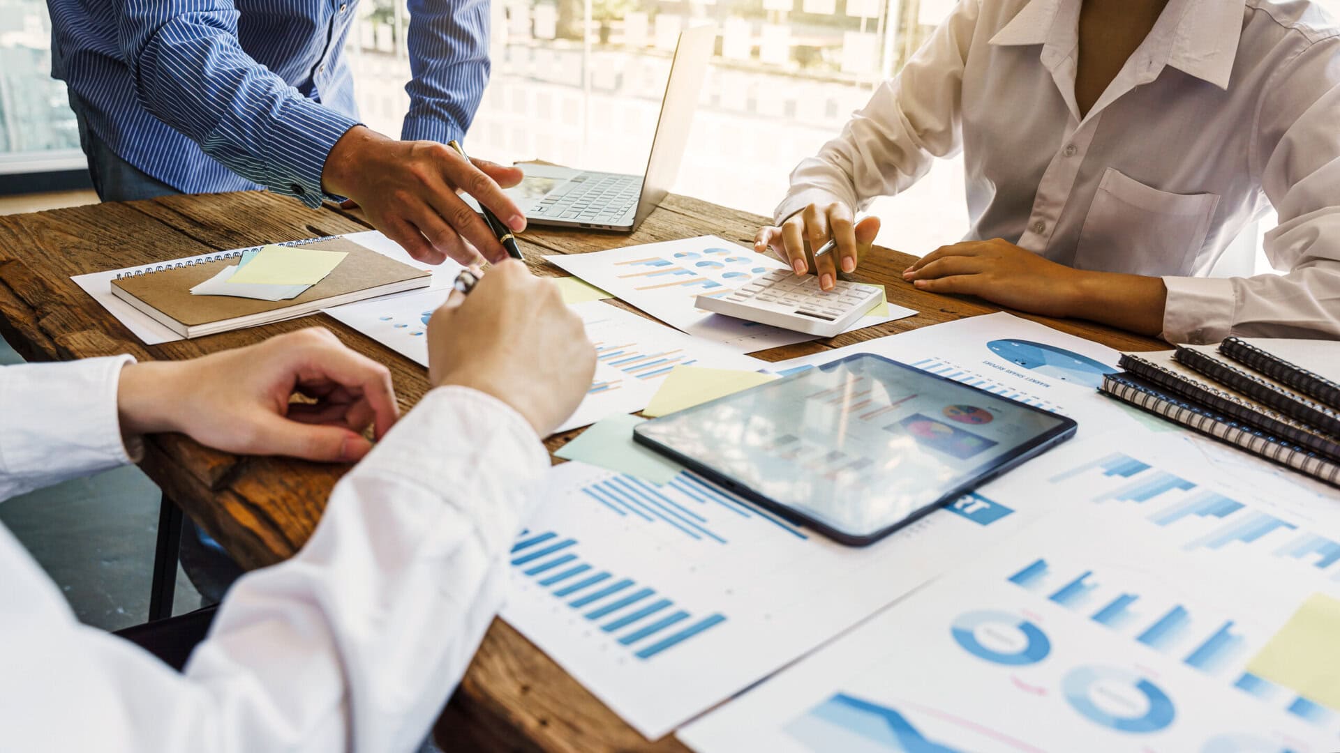 Hands of business team people meeting and discussing with business statistics paper charts.